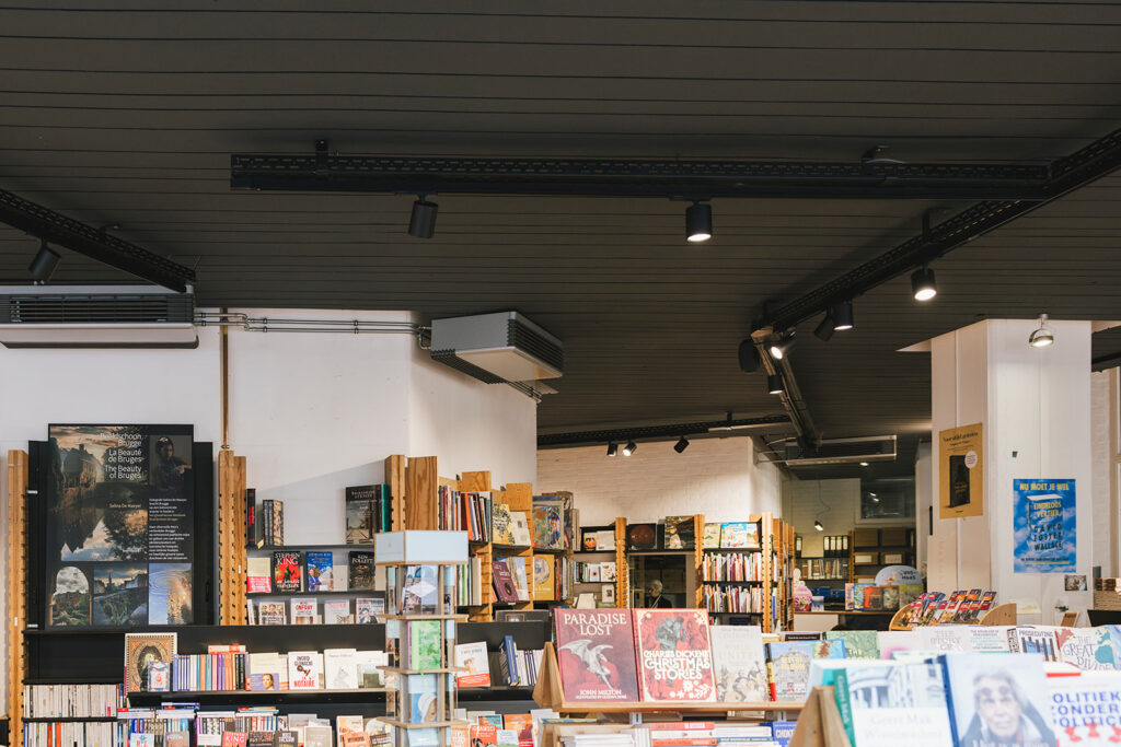 verlichte boekenwinkel met moderne zwarte spots en houten rekken binnen elektro pacco