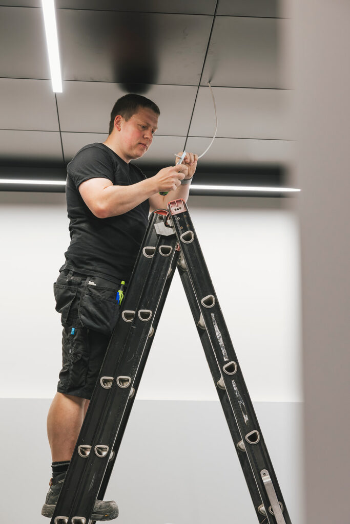 elektricien op ladder werkt aan bedrading in plafond elektropacco in zedelgem