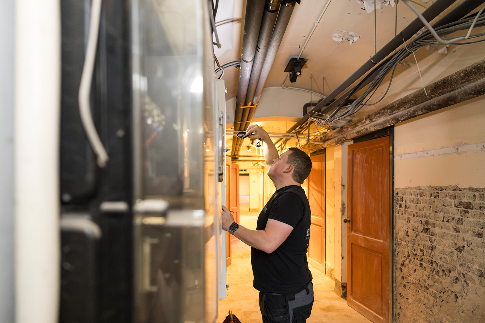 elektricien van electro pacco werkt aan schakelkast in technische gang