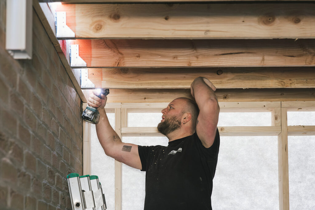 elektricien van electro pacco installeert verlichting onder houten plafond in woning