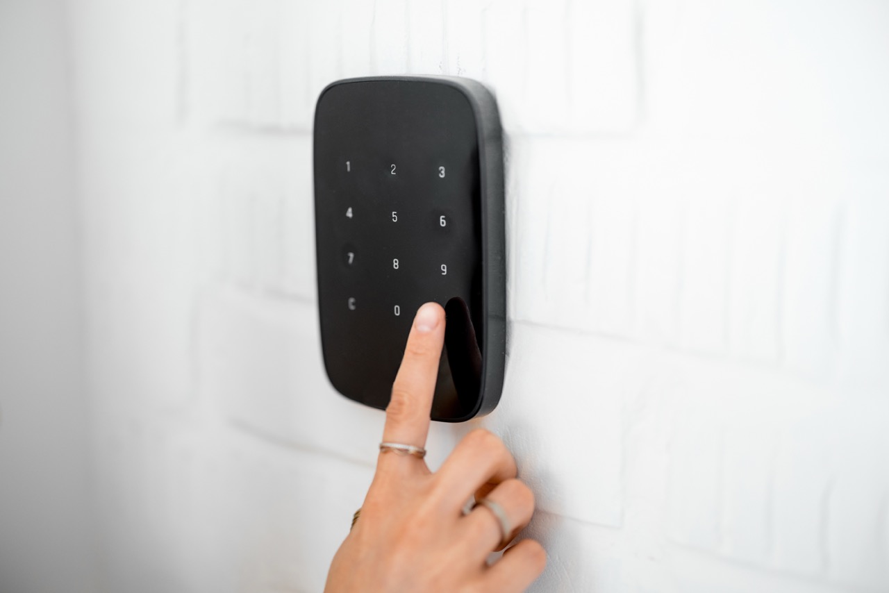 hand die code invoert op een zwart digitaal codeslot aan witte muur voor veiligheid