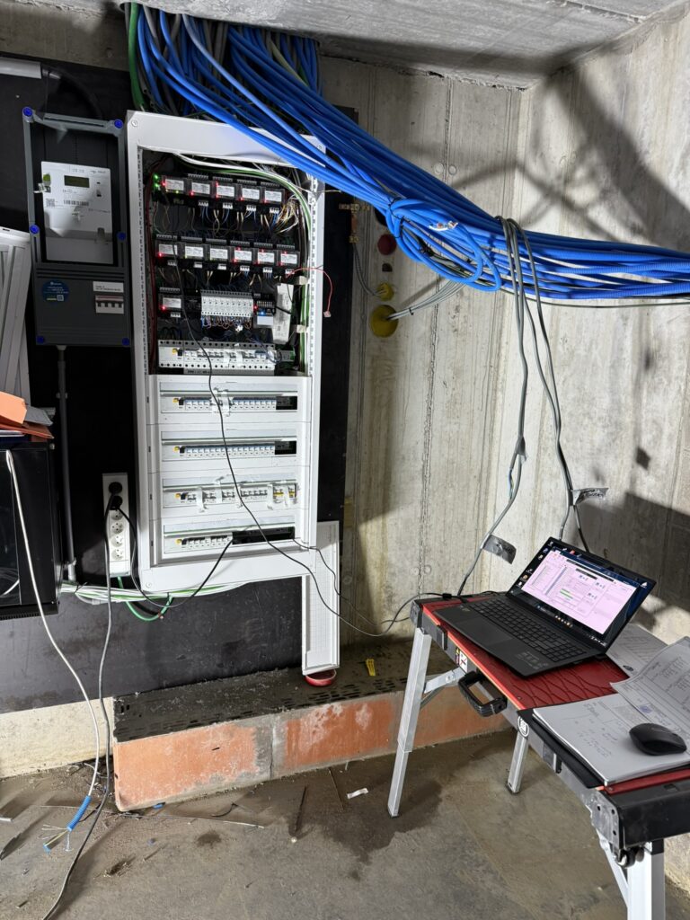 elektrische verdeelkast met blauwe kabels en laptop voor installatie door Electro Pacco in Zedelgem