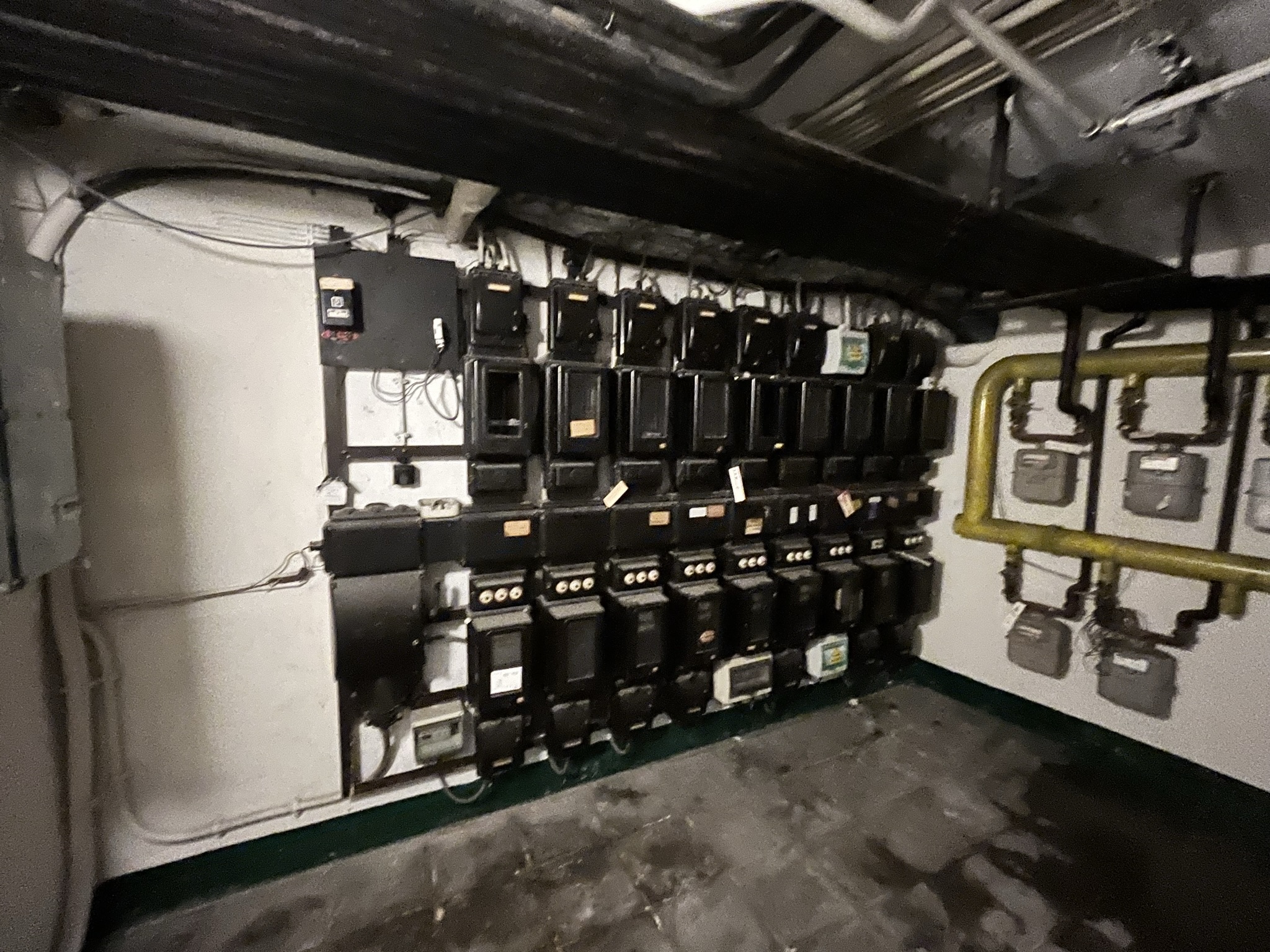 oude elektriciteitsmeters en leidingen in technische ruimte van gebouw met gasmeters