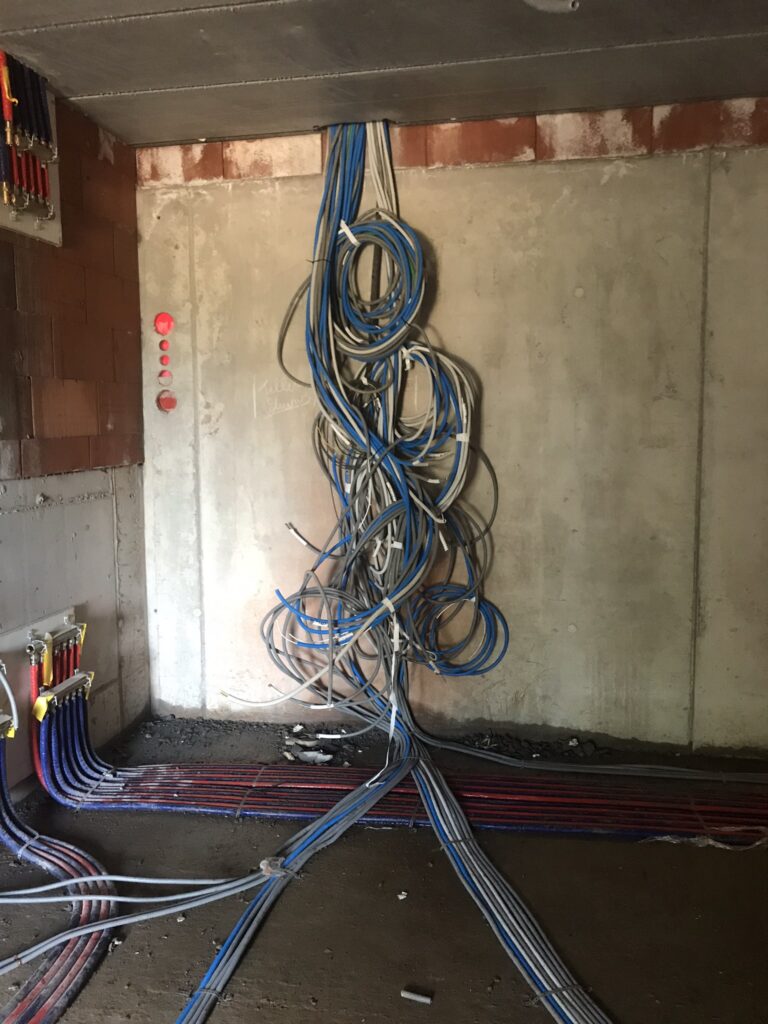 elektriciteitskabels blauw en grijs lopend van vloer naar plafond in bouwfase door electro pacco